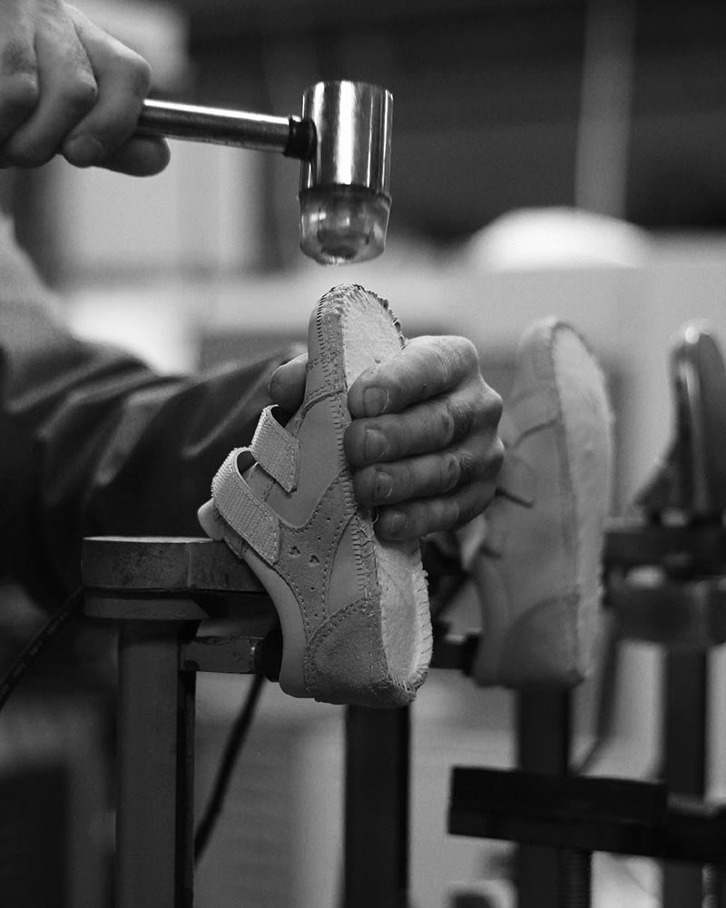 Håndværker i Bundgaard-skoværksted former børnesko med præcision – traditionel skoproduktion med fokus på kvalitet og håndværk.